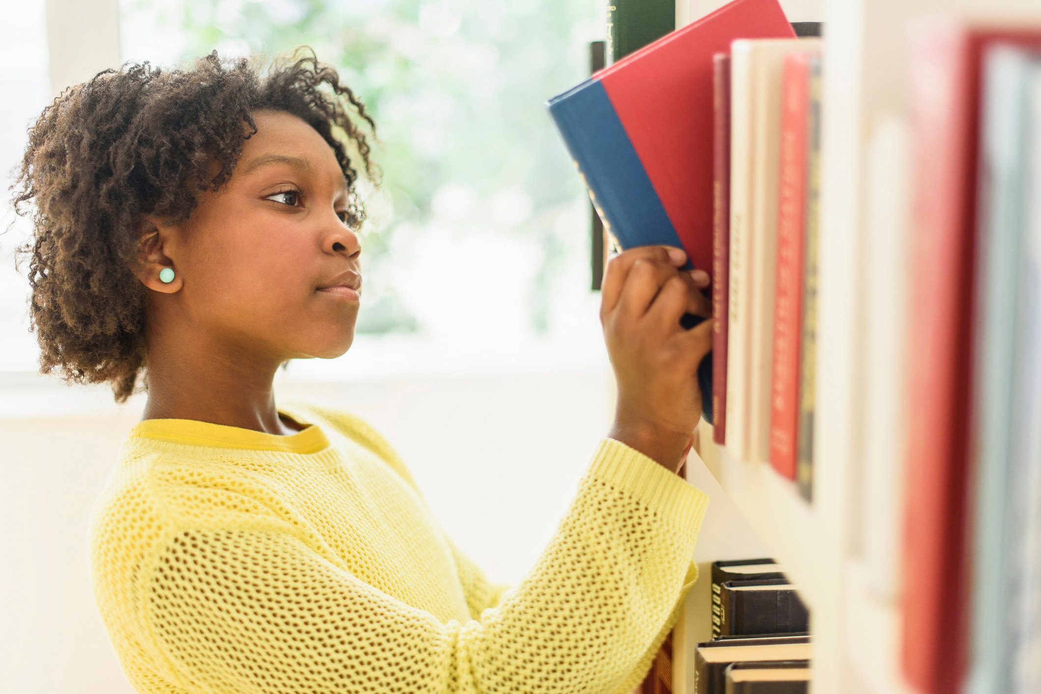 Student Choosing Book from Library Shelf