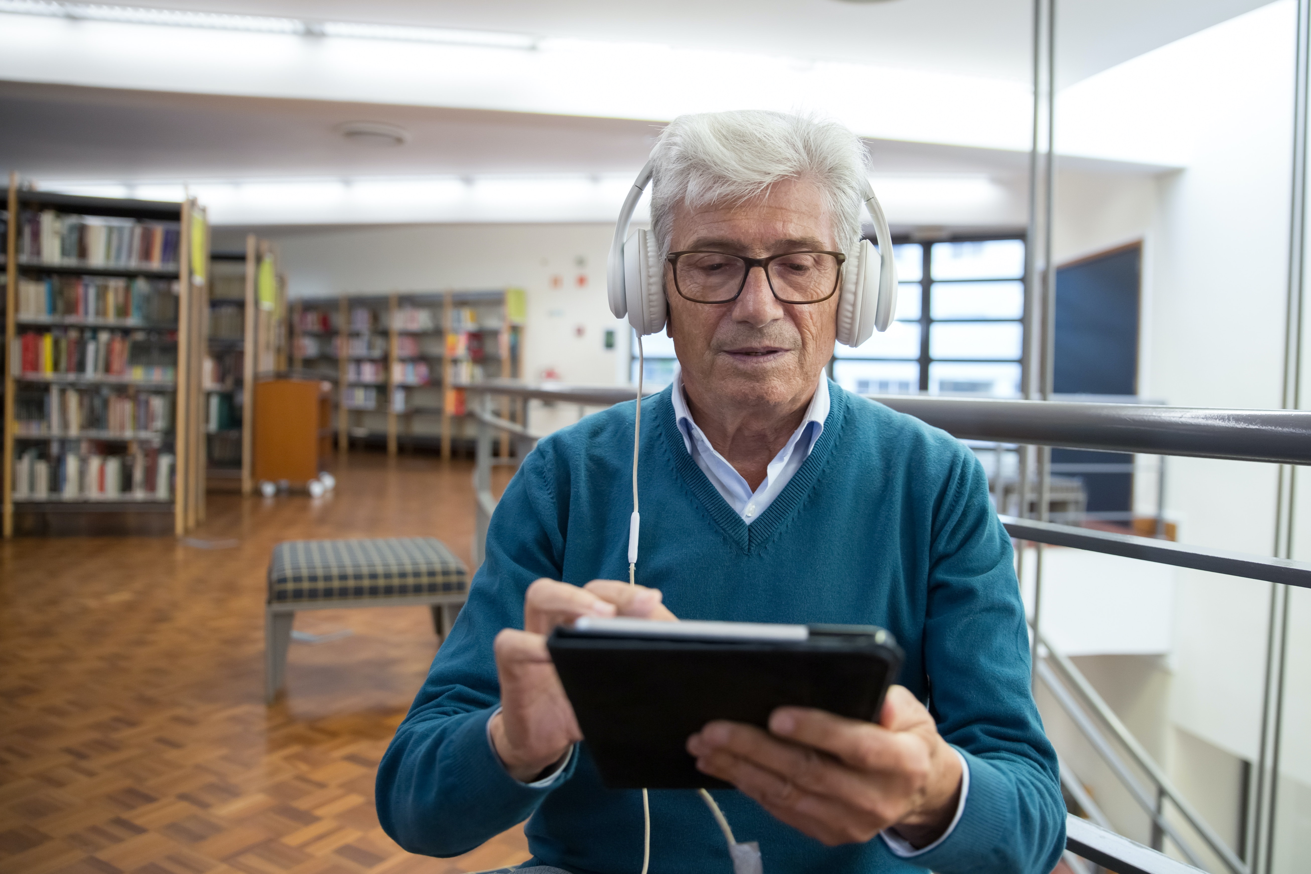 Older man using a tablet with headphones on