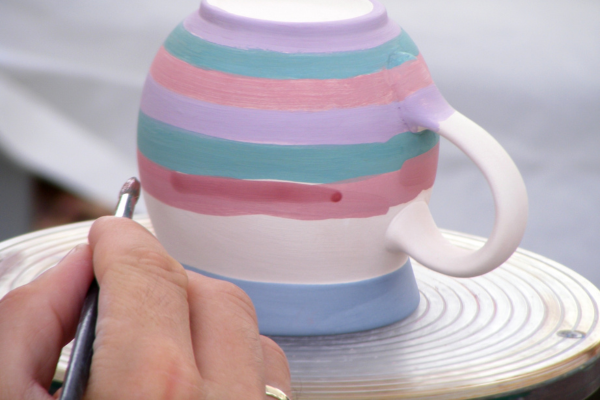 Image: A person painting a ceramic mug