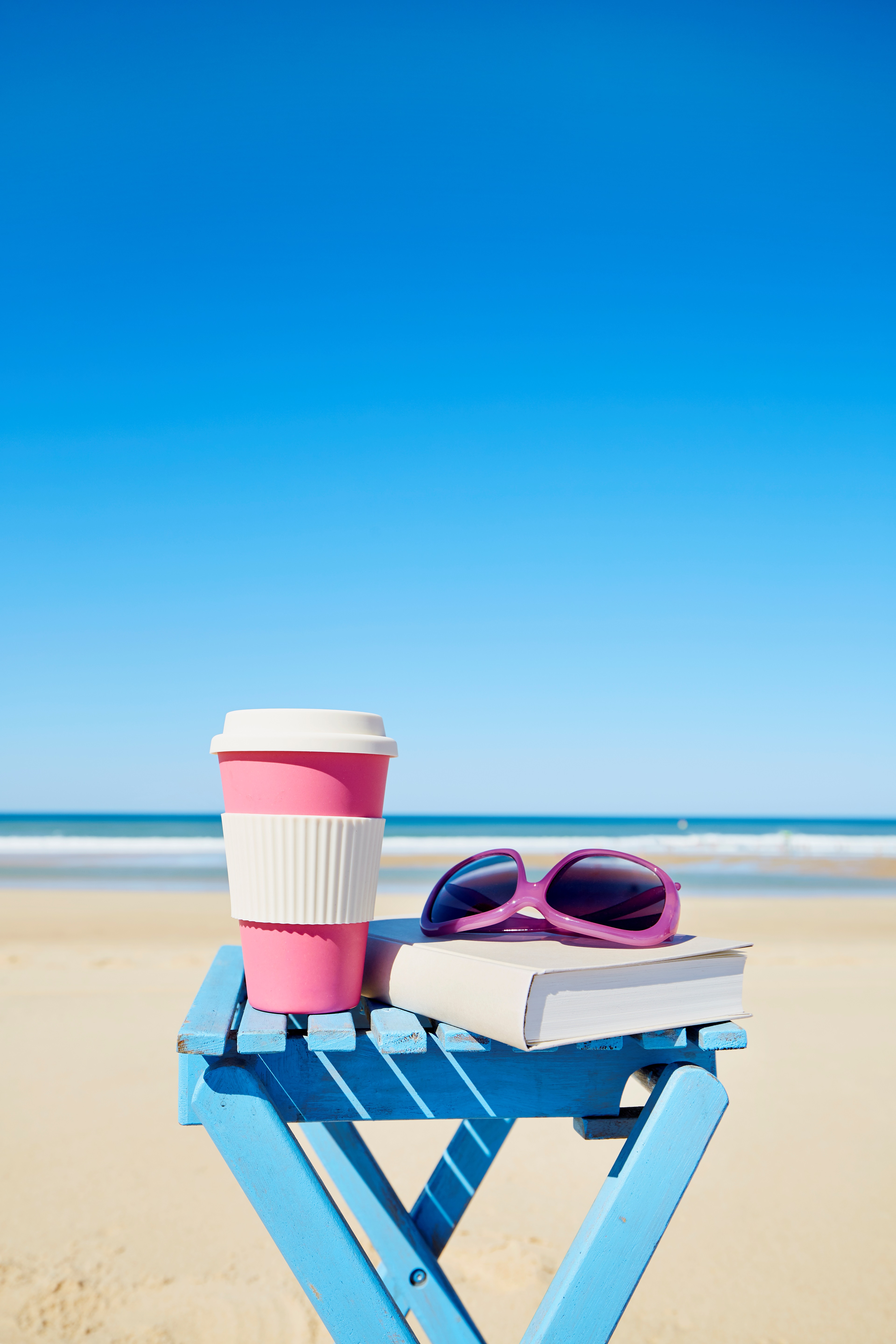 Coffee with Sunglasses and Book on Beachside Table