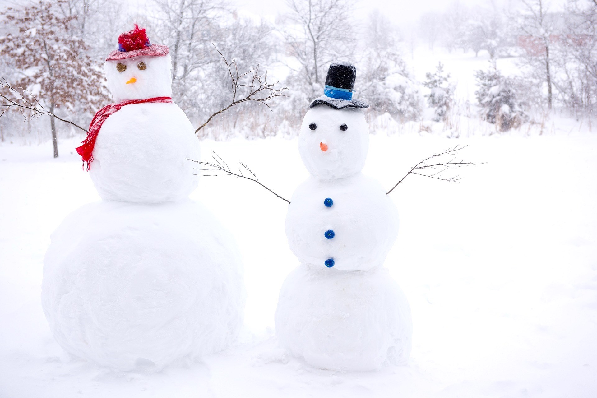 A photograph of two snowmen, wearing hats.