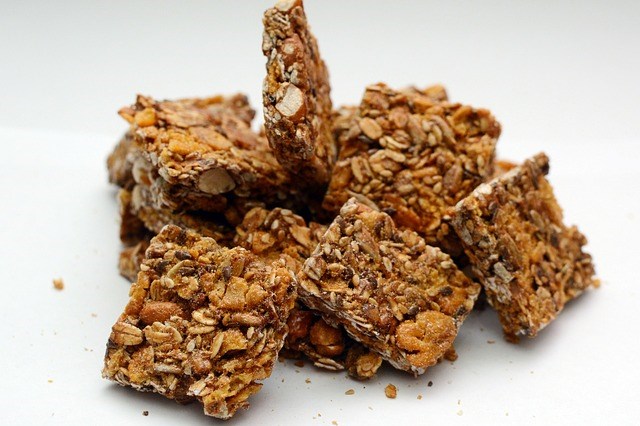A photo of pieces of a granola bar in a pile, on a plain background.