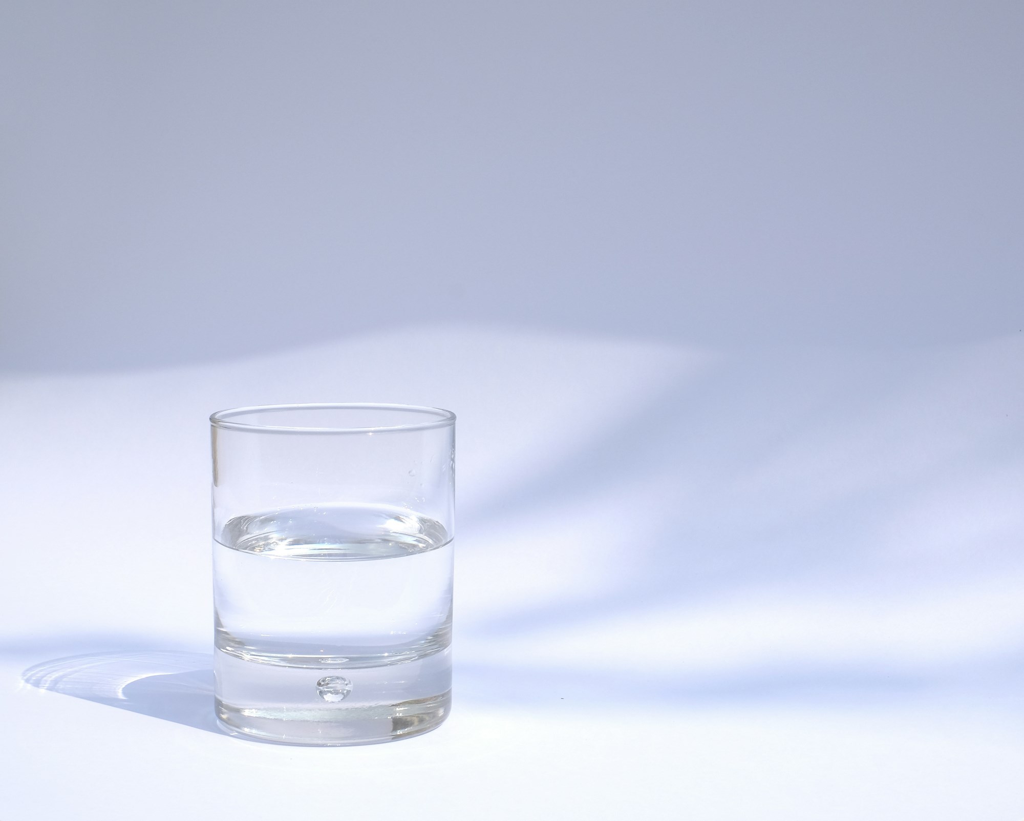 A photo of a glass of water sitting on a white surface.