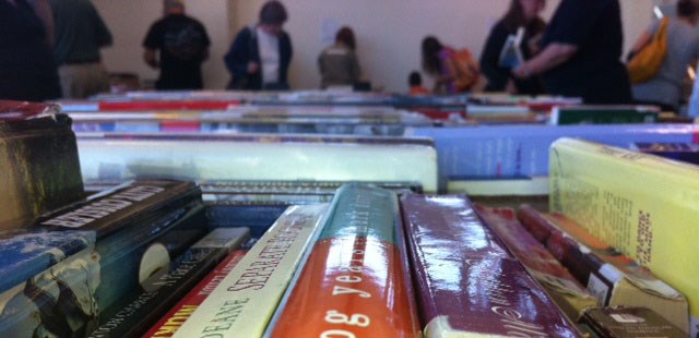 A photo of books and shoppers at a used book sale.