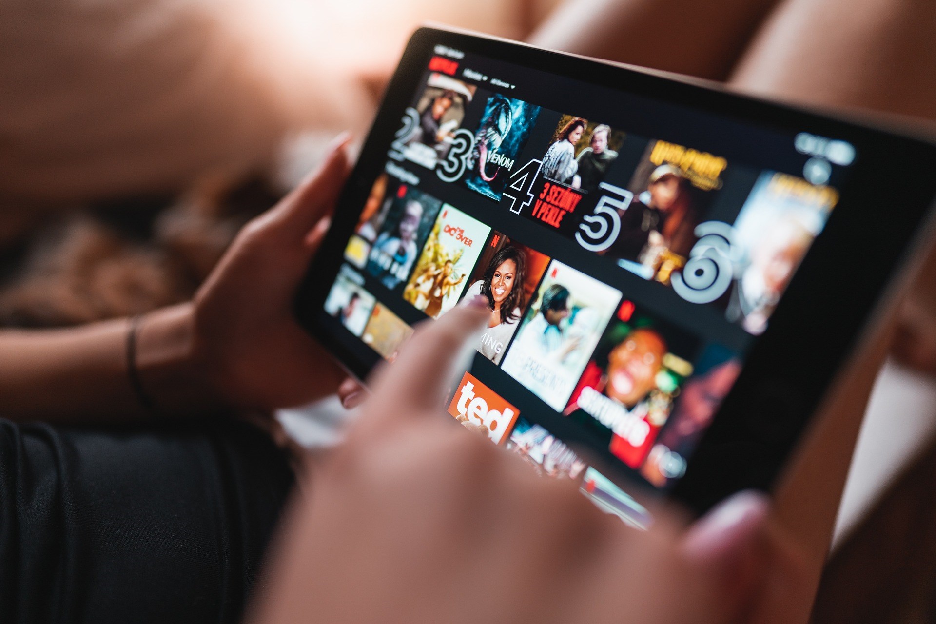 A close up photo of someone selecting something to watch on a tablet.