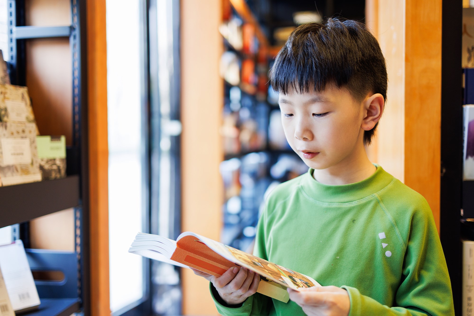 A photo of a child standing and reading a book.