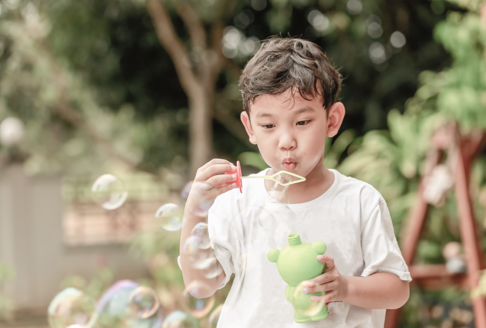 Child blowing blubbles outside