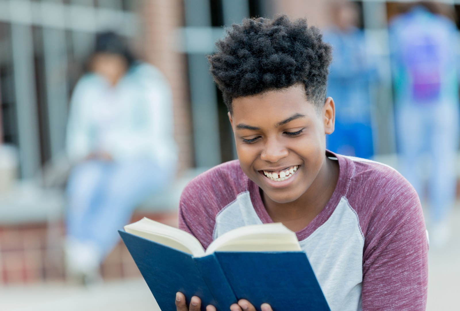 Teen boy reading a book and smiling
