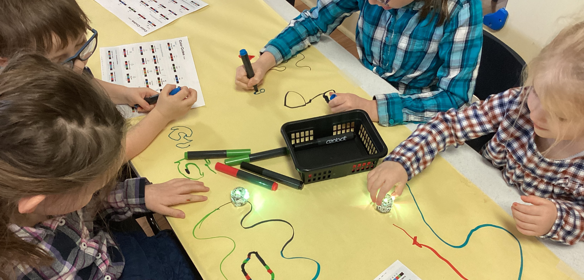 An overhead image of children playing with ozobot coding critters.