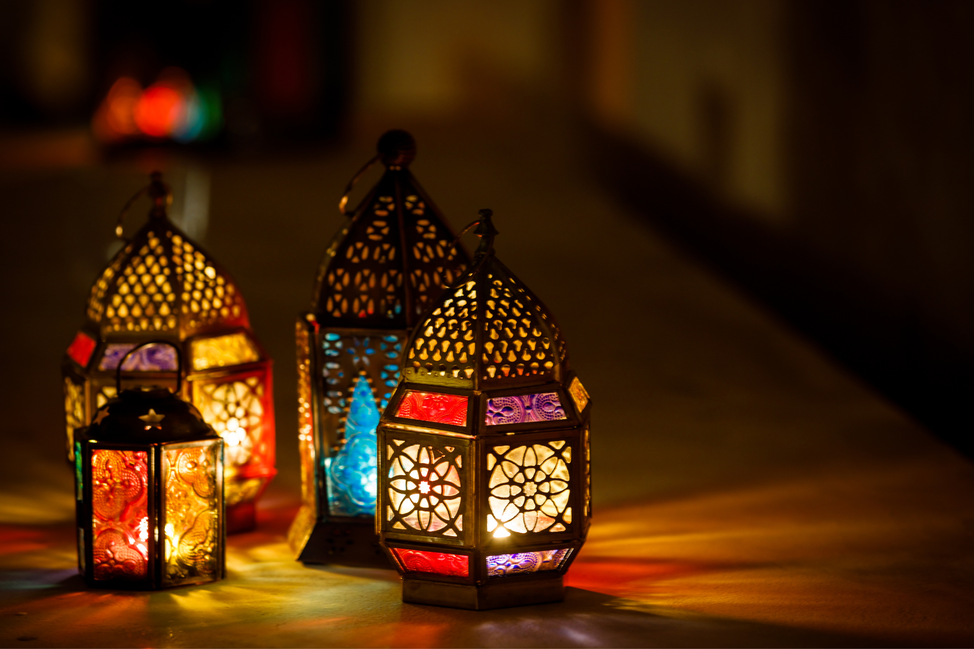 Four lit lanterns sit atop a table.