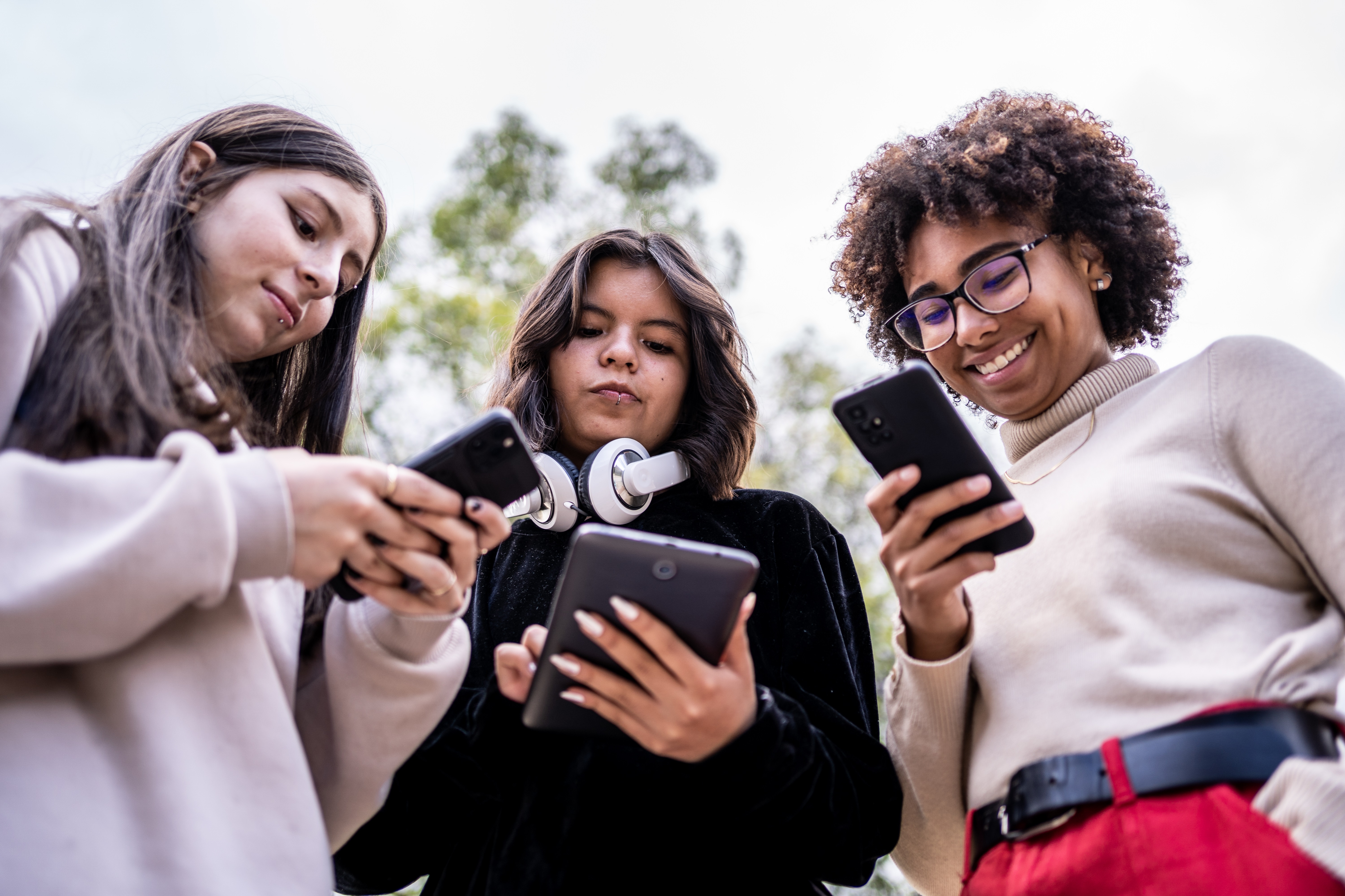 Young Friends using Mobile Phone and Digital Tablet at Outdoors