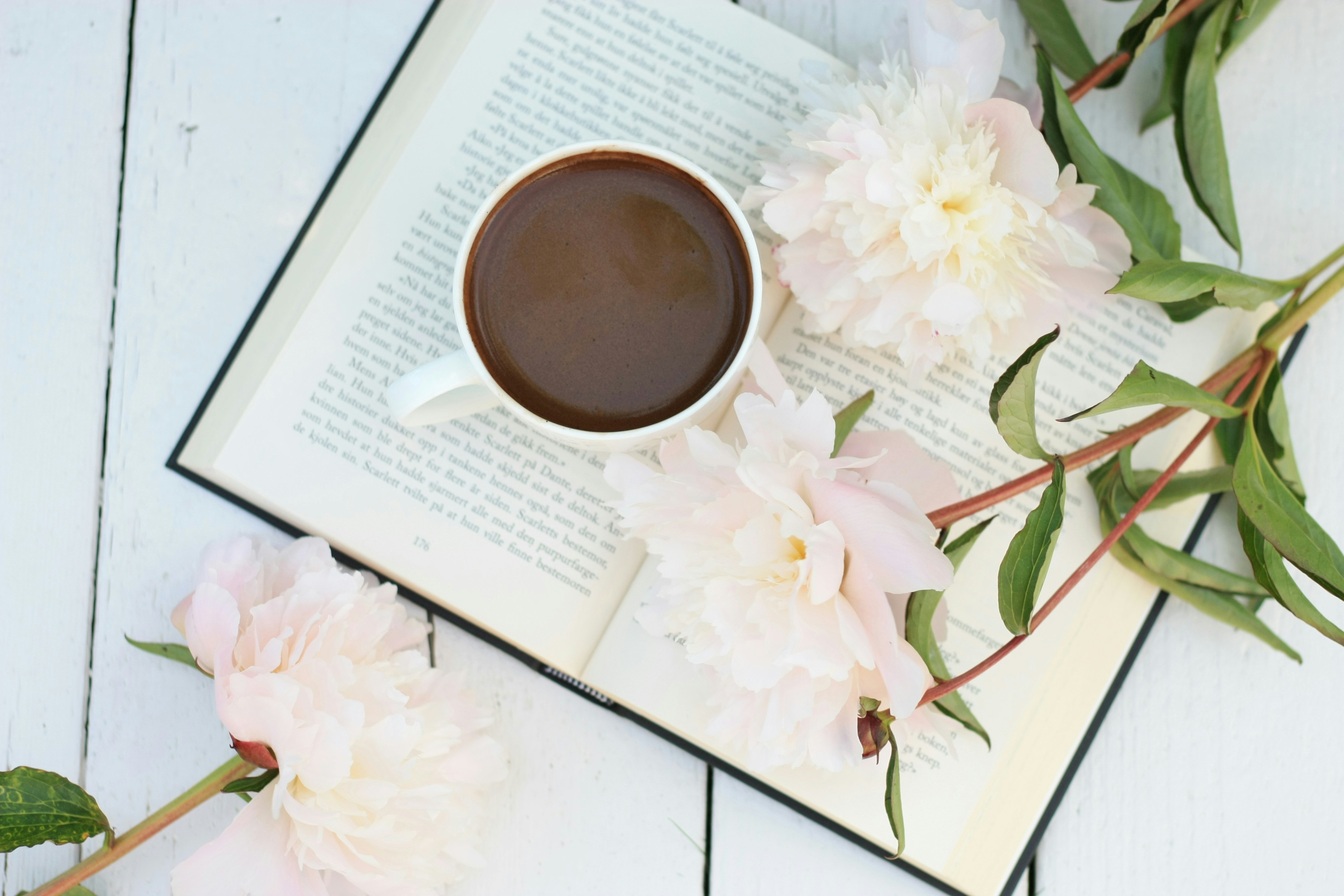 A Cup of Coffee on Top of a Book With Pink Flowers