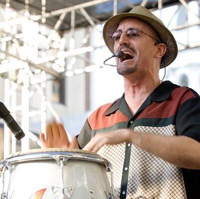 drummer with glasses and hat singing into a microphone