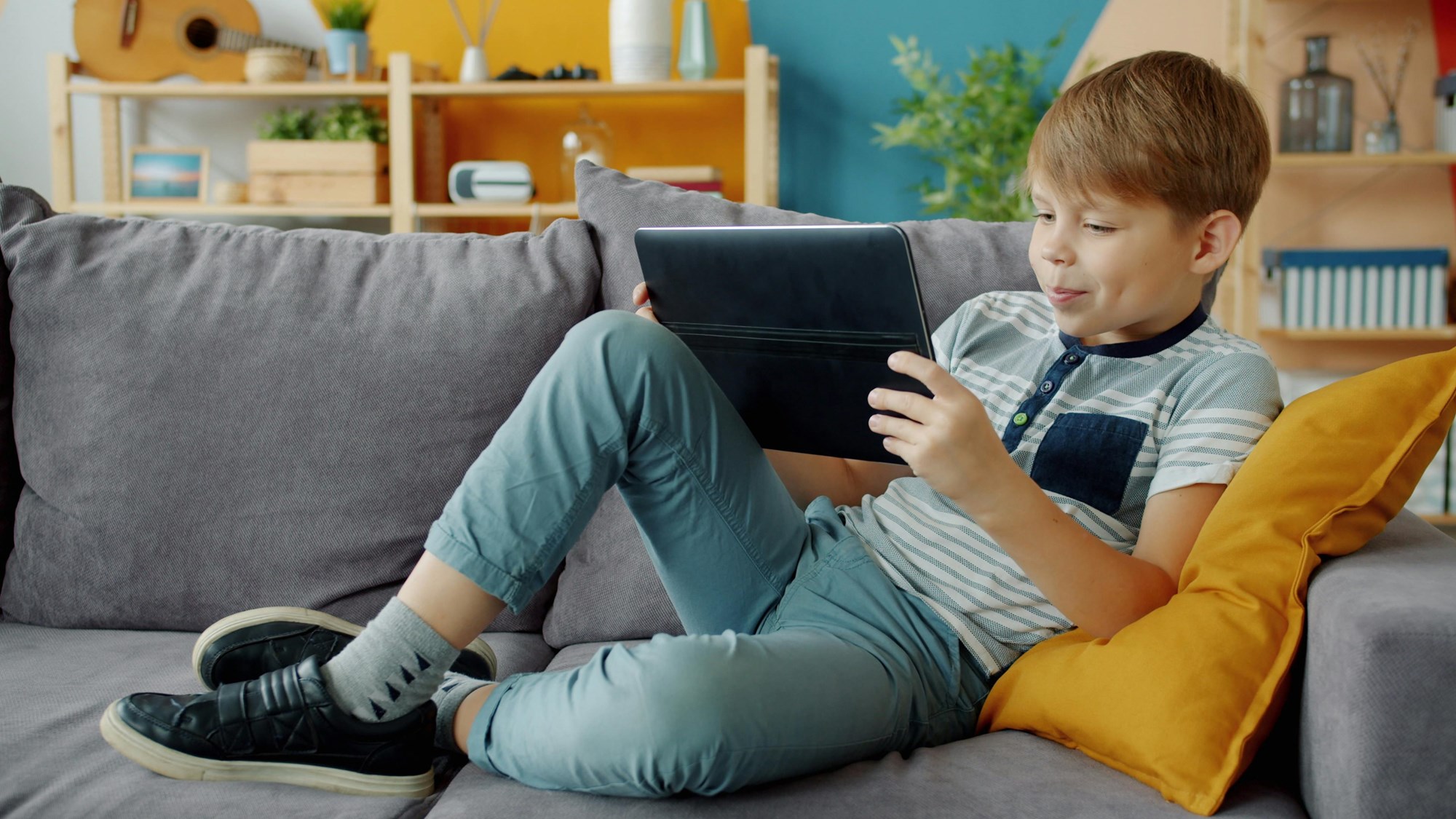 Young Boy Relaxing with Tablet on Couch