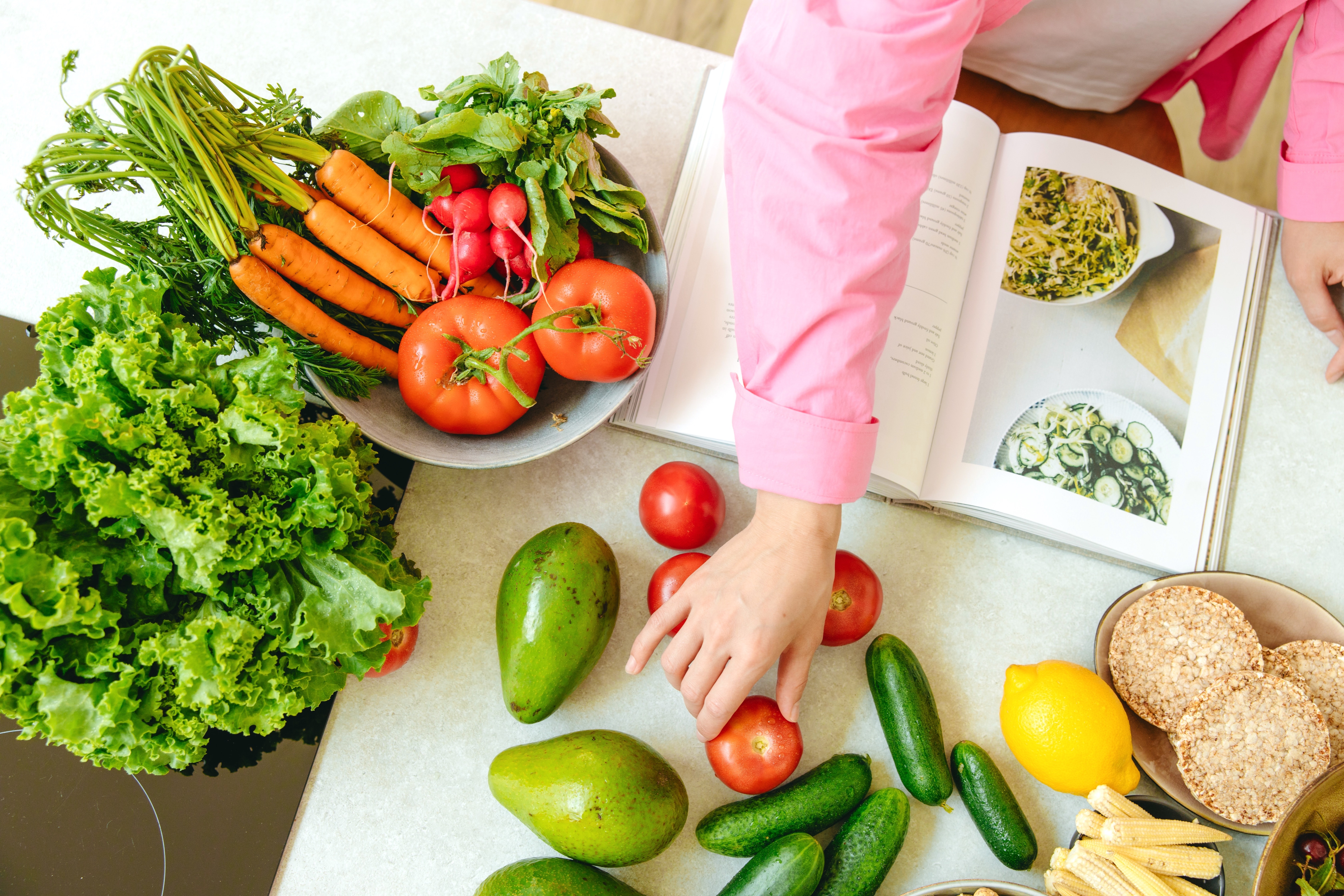 Woman Cooking with a Cookbook and Vegetables