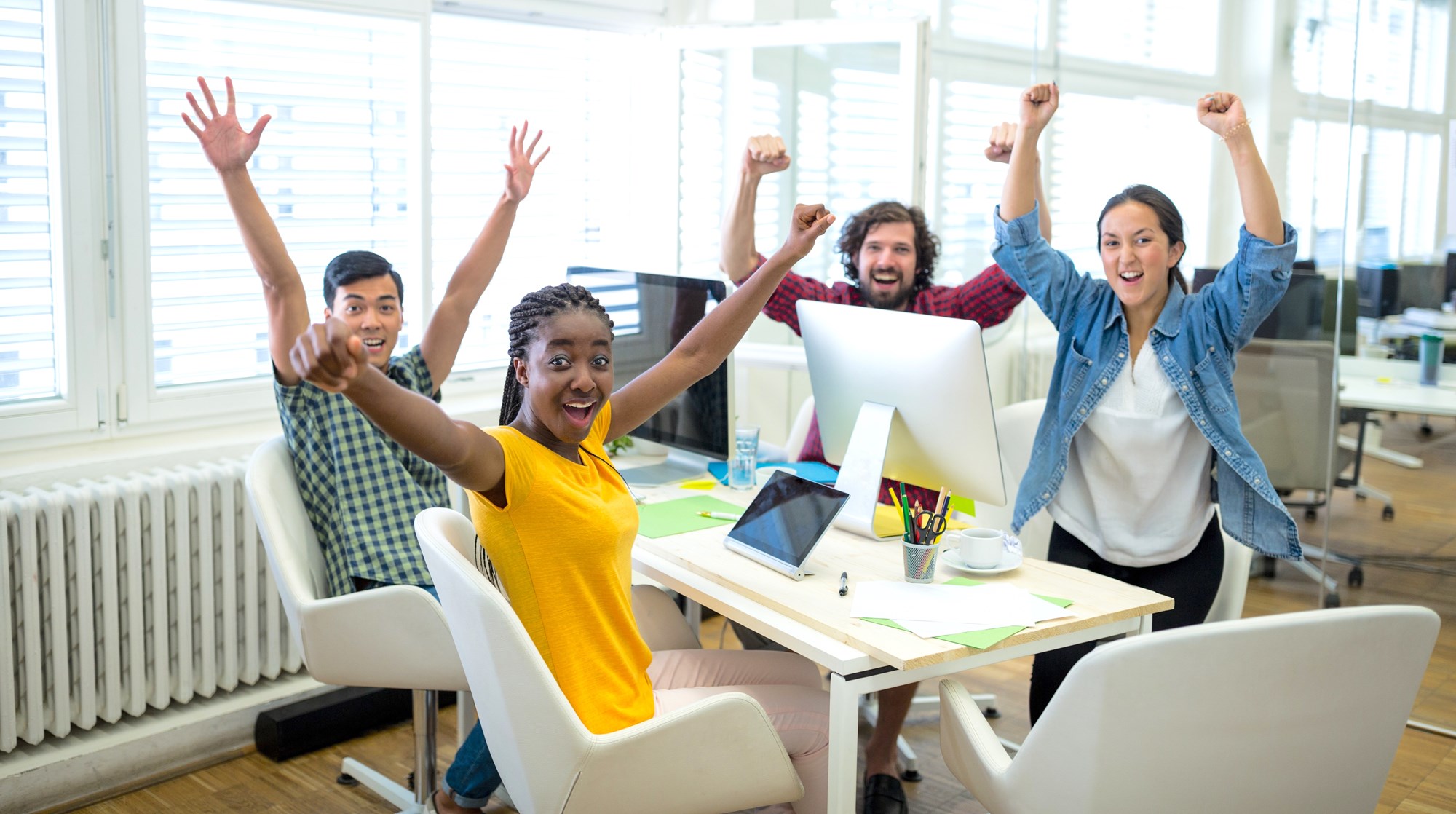 Group of excited coworkers at a table in the office Group of excited coworkers at a table in the office