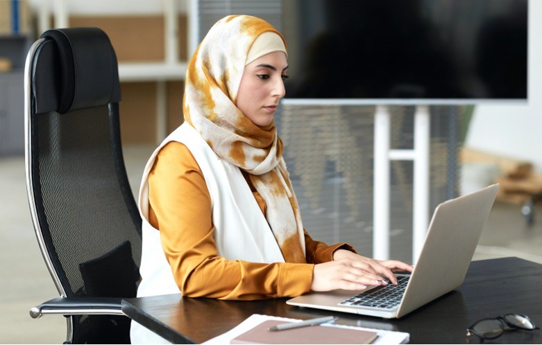 Woman wearing a type of hijab uses laptop at a library