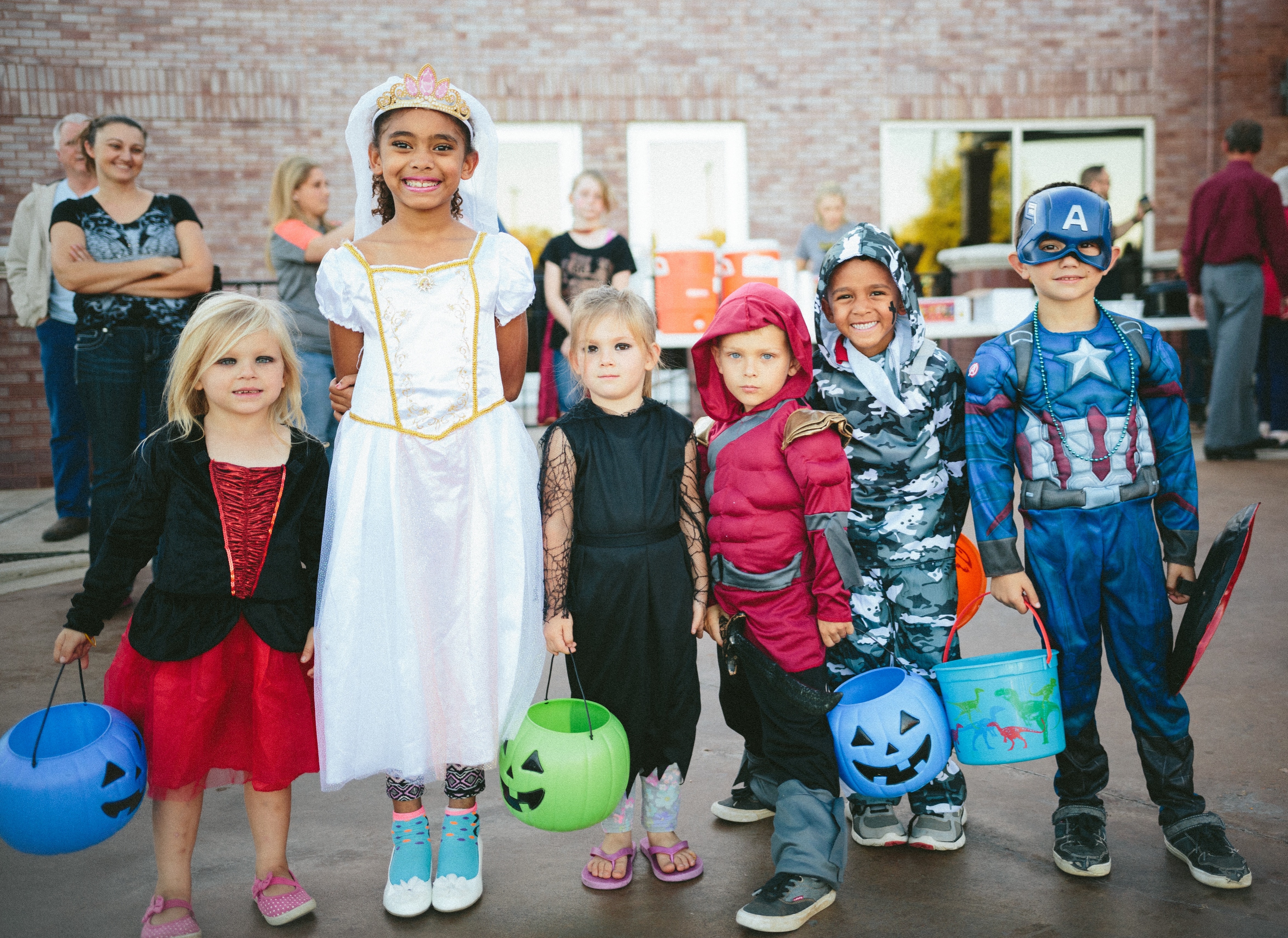 Children in Halloween costumes holding pumpkin buckets
