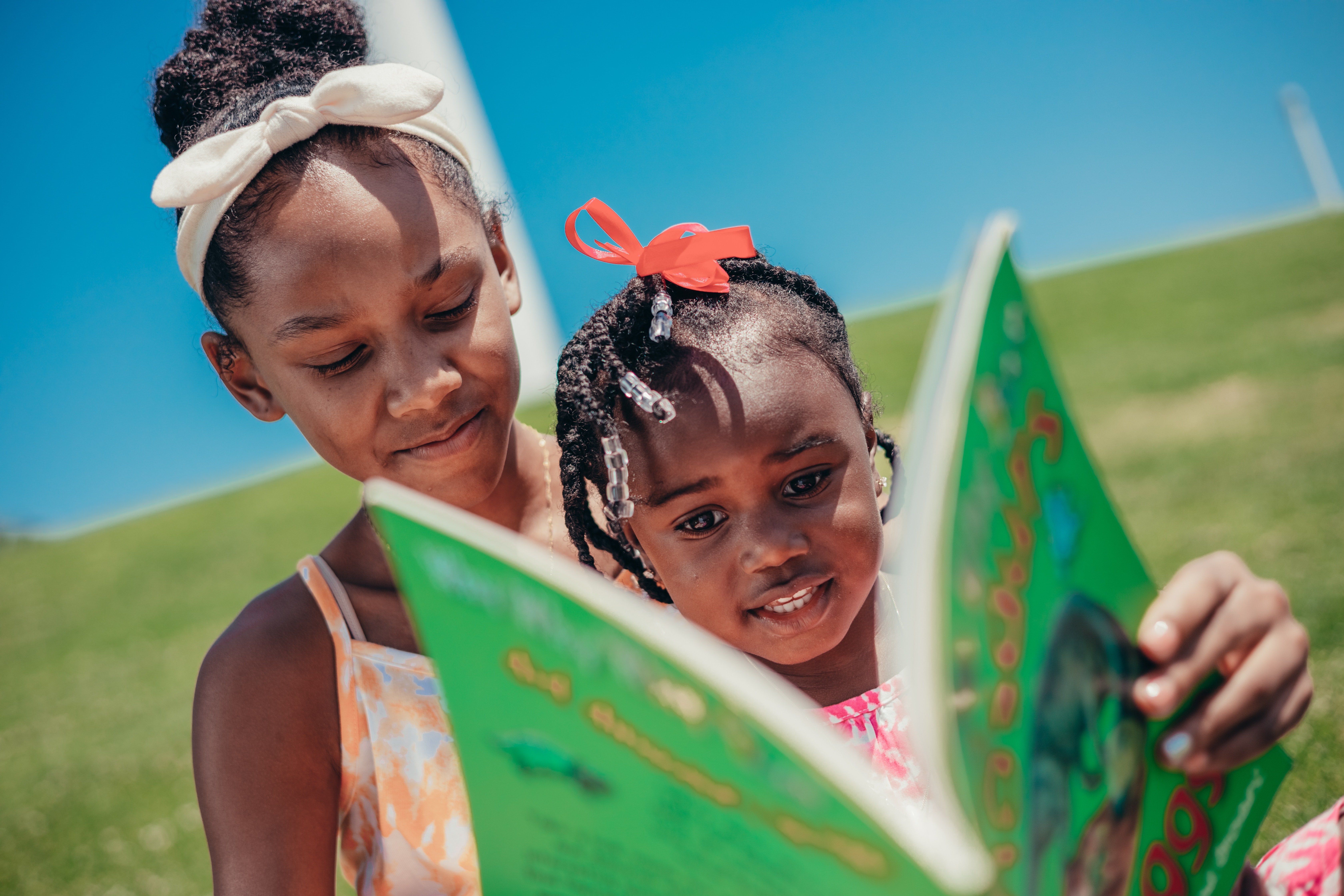 Two Sisters Reading a Book Outdoors
