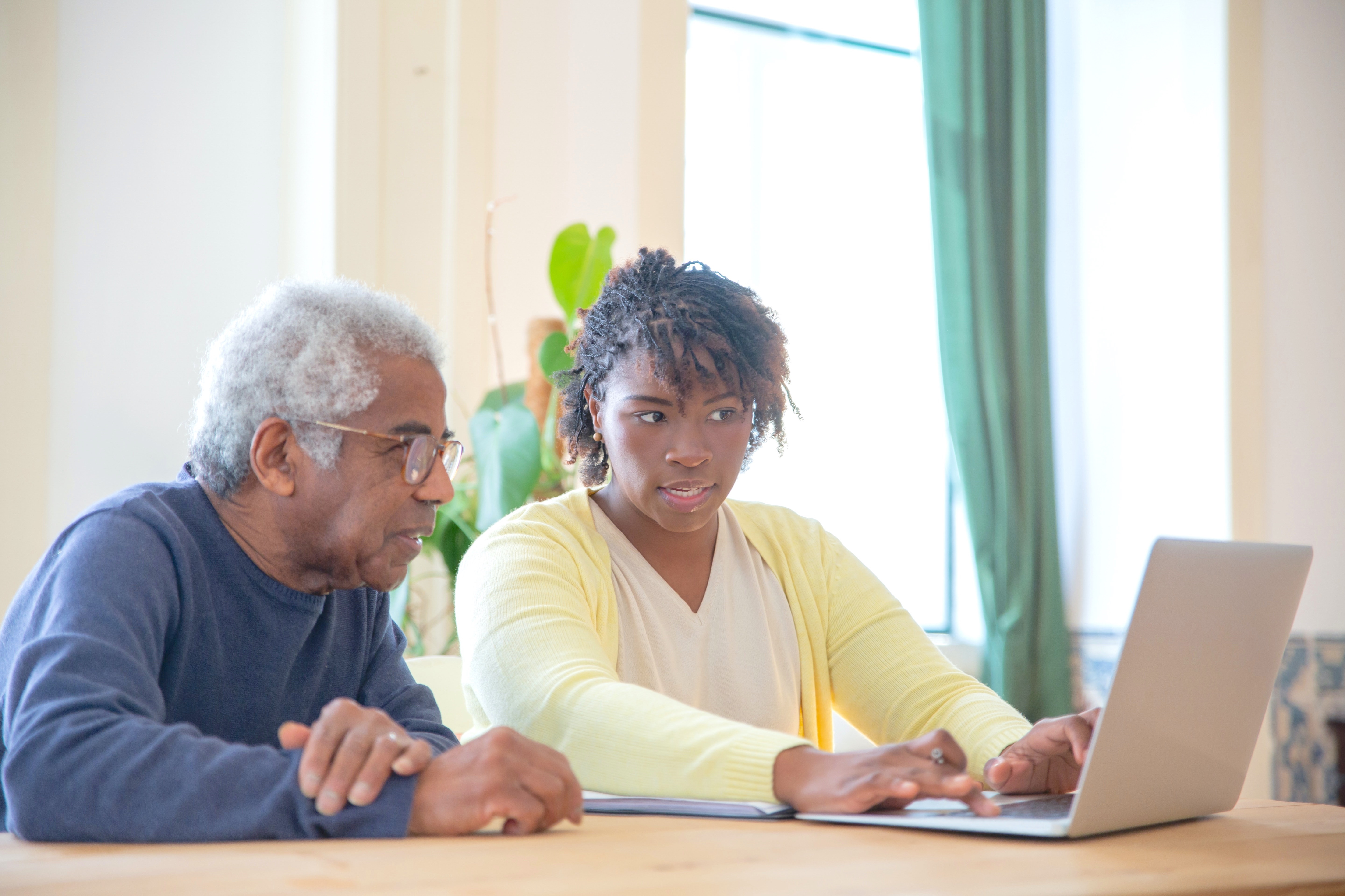 Older Adult Sitting with Young Woman Using Laptop