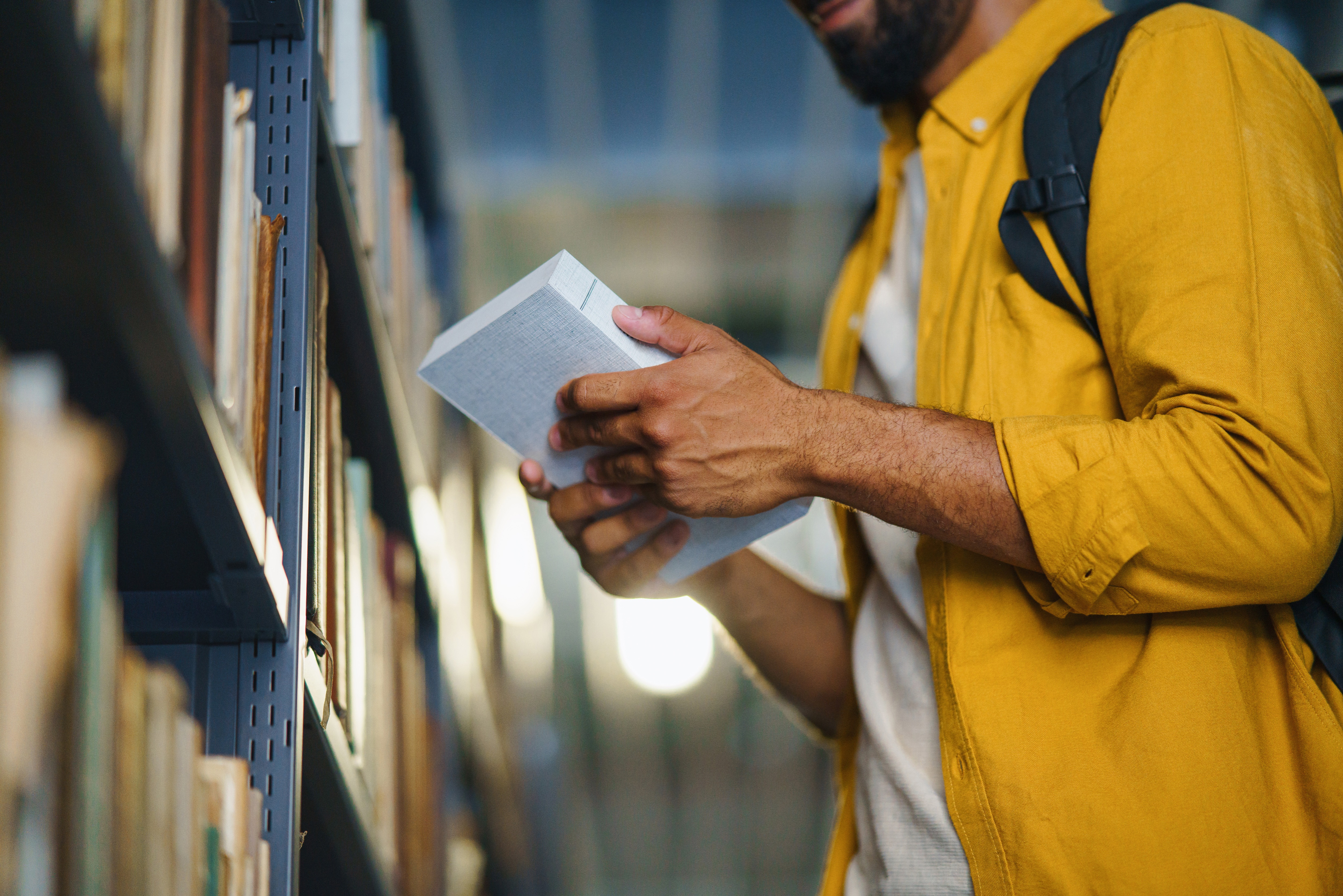 University Student With Book in Library
