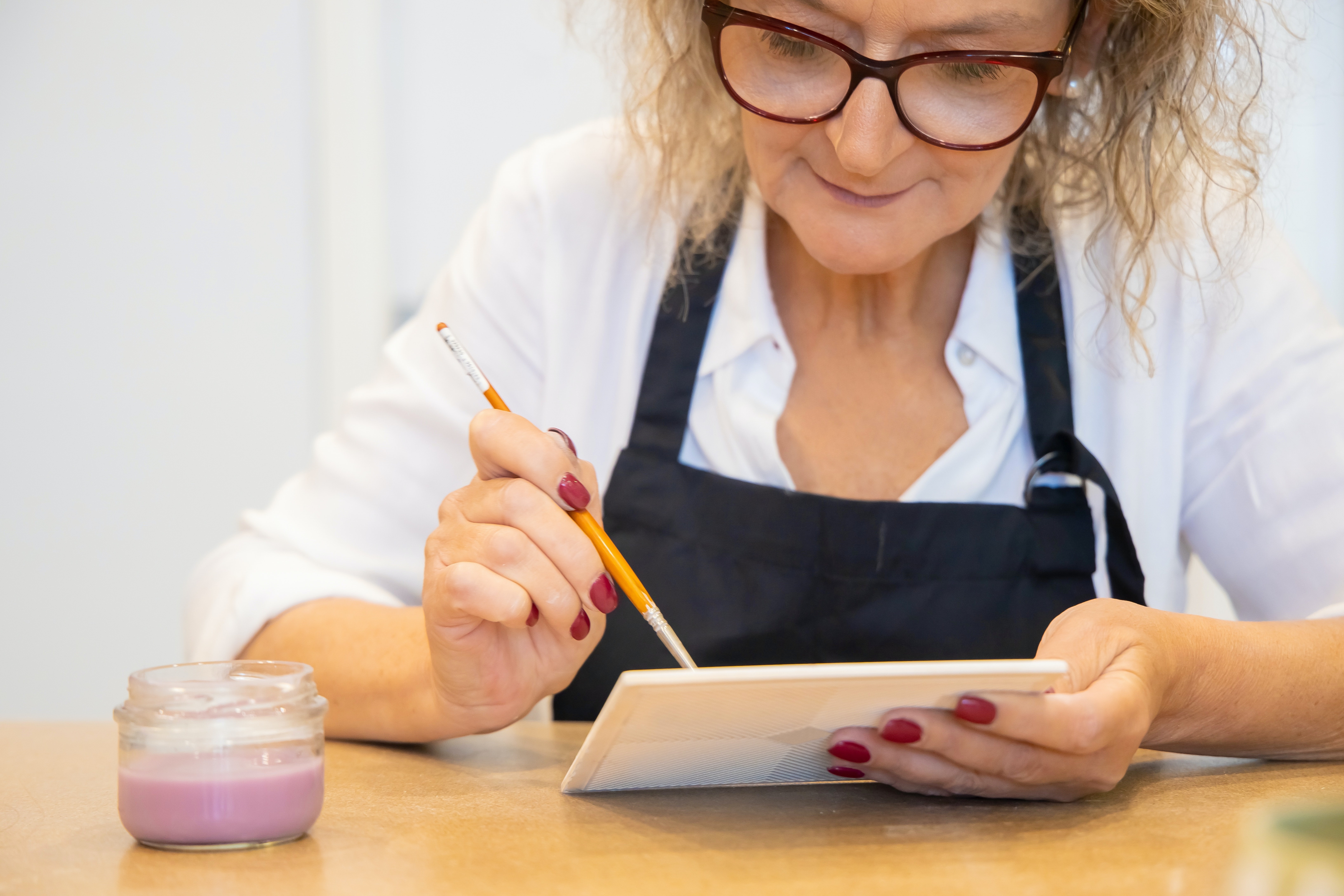 Senior Woman Writing on a White Paper With a Painting Brush