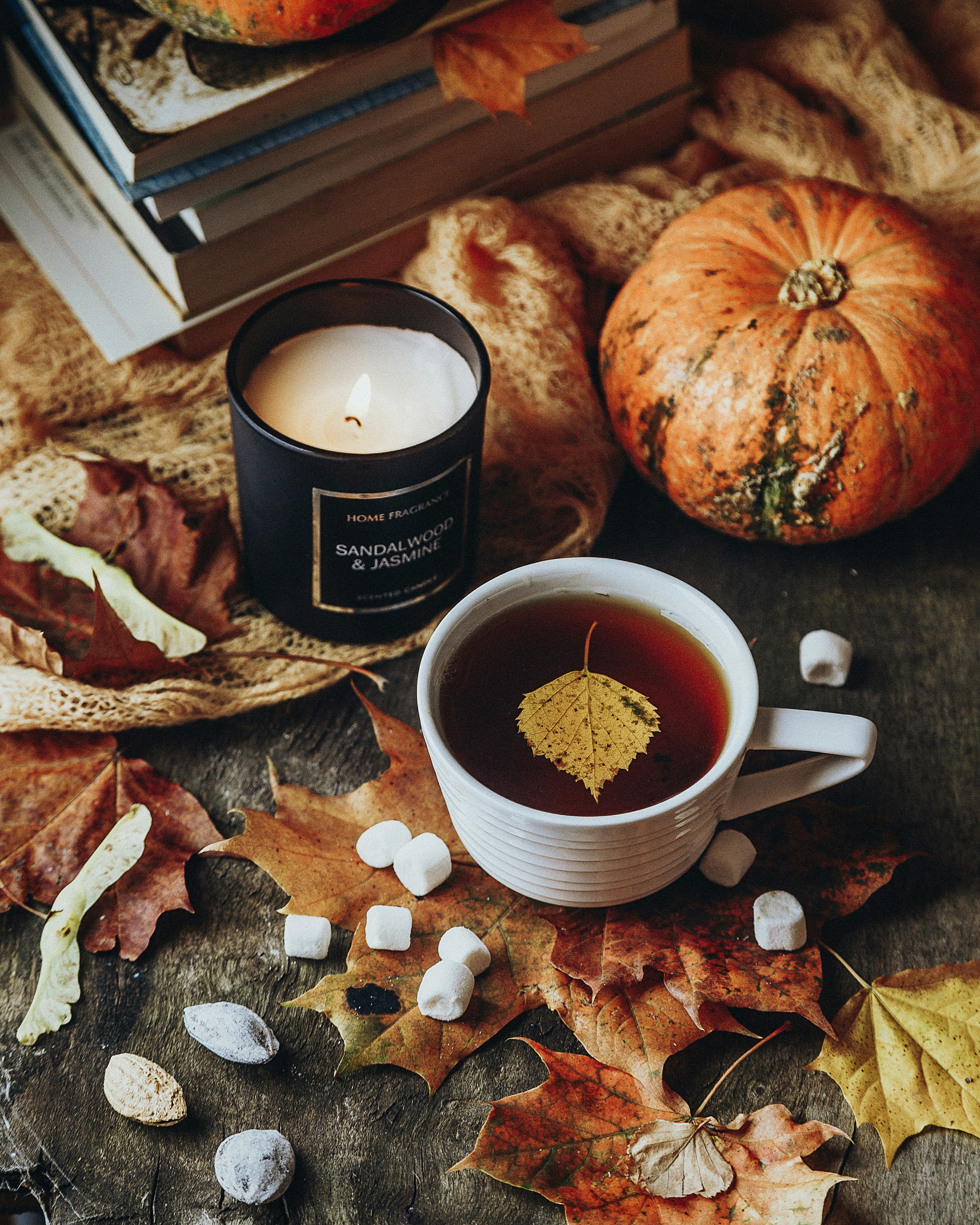 White Tea Cup On Brown Wooden Table with Pumpkin and Books
