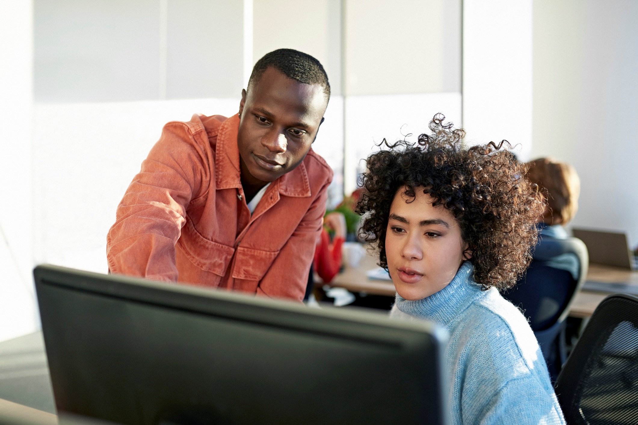 Two Adults Looking Over Computer Together in Classroom
