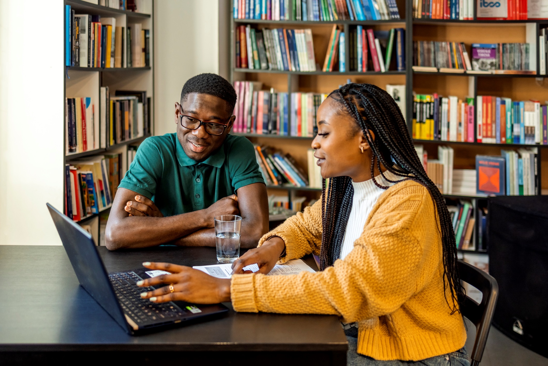 Two Young Adults Looking at Laptop in Library