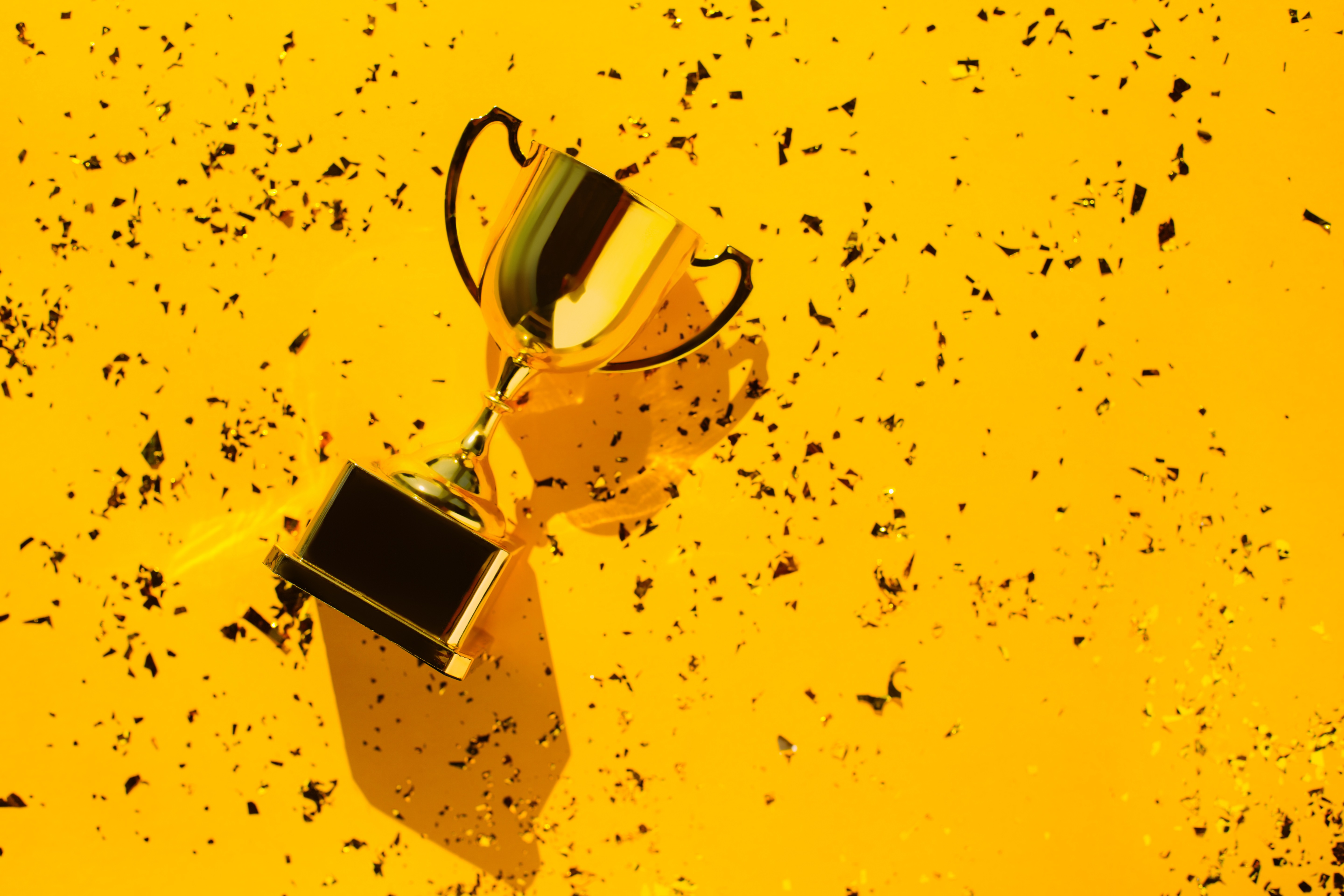 Top View of Metallic Golden Goblet on Bright Yellow Background