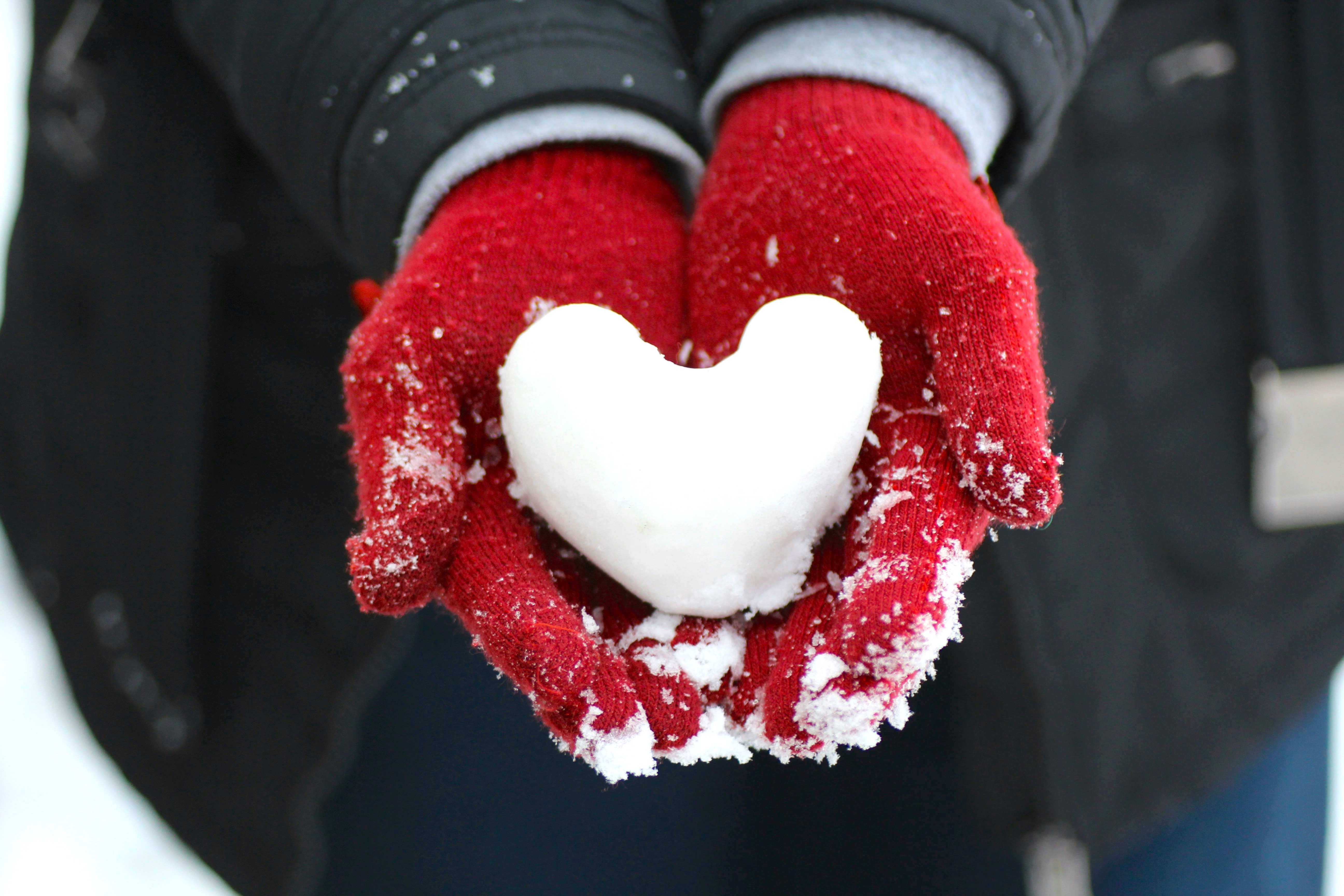 Person with Red Mittens Holding Snow Shaped into a Heart
