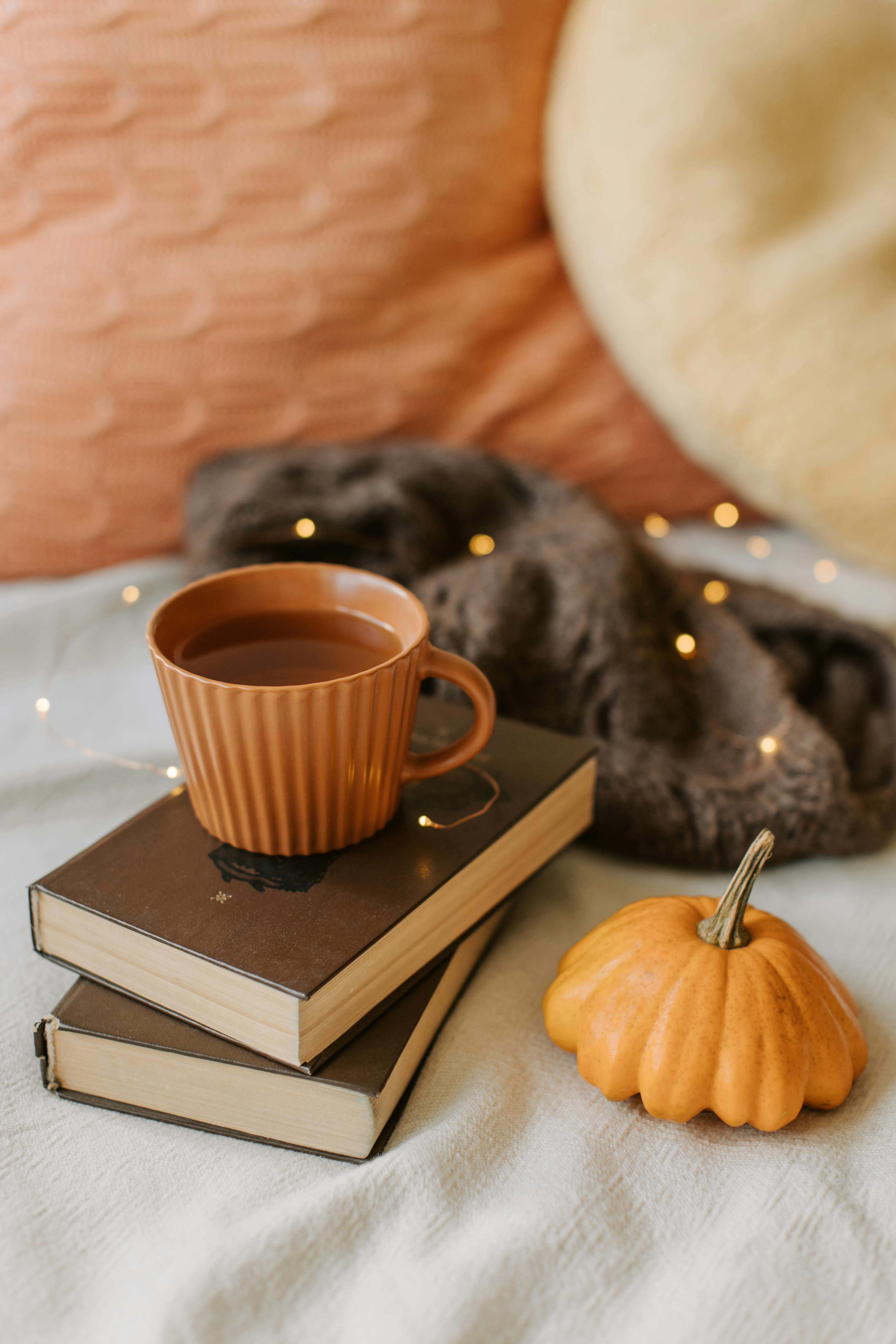 Cup of Tea on Books Next to a Pumpkin and Brown Sweater
