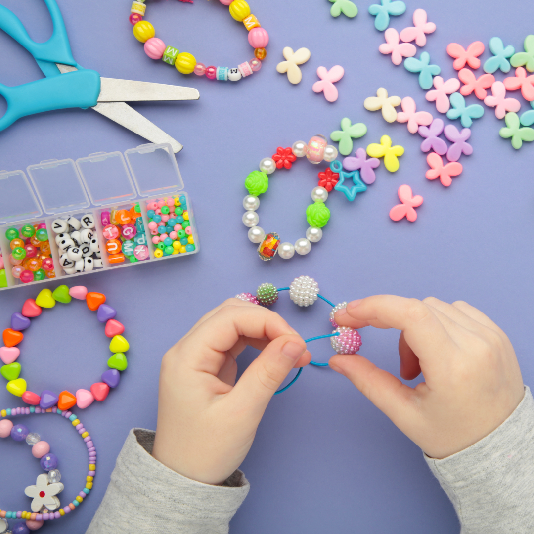 Photo: child's hands making beaded bracelets