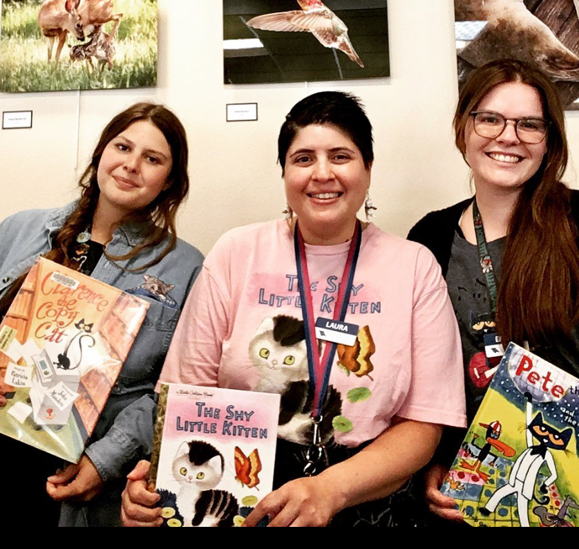 Three librarians holding books about cats