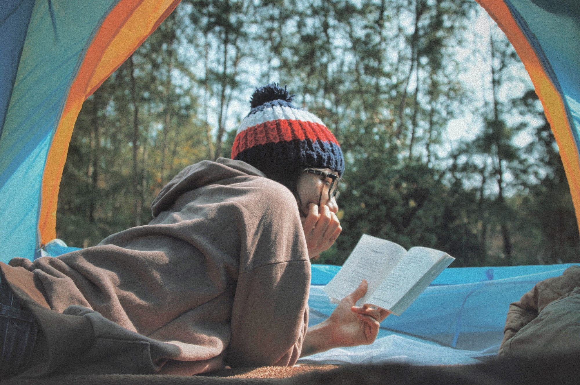 Woman Reading a Book in a tent facing forest