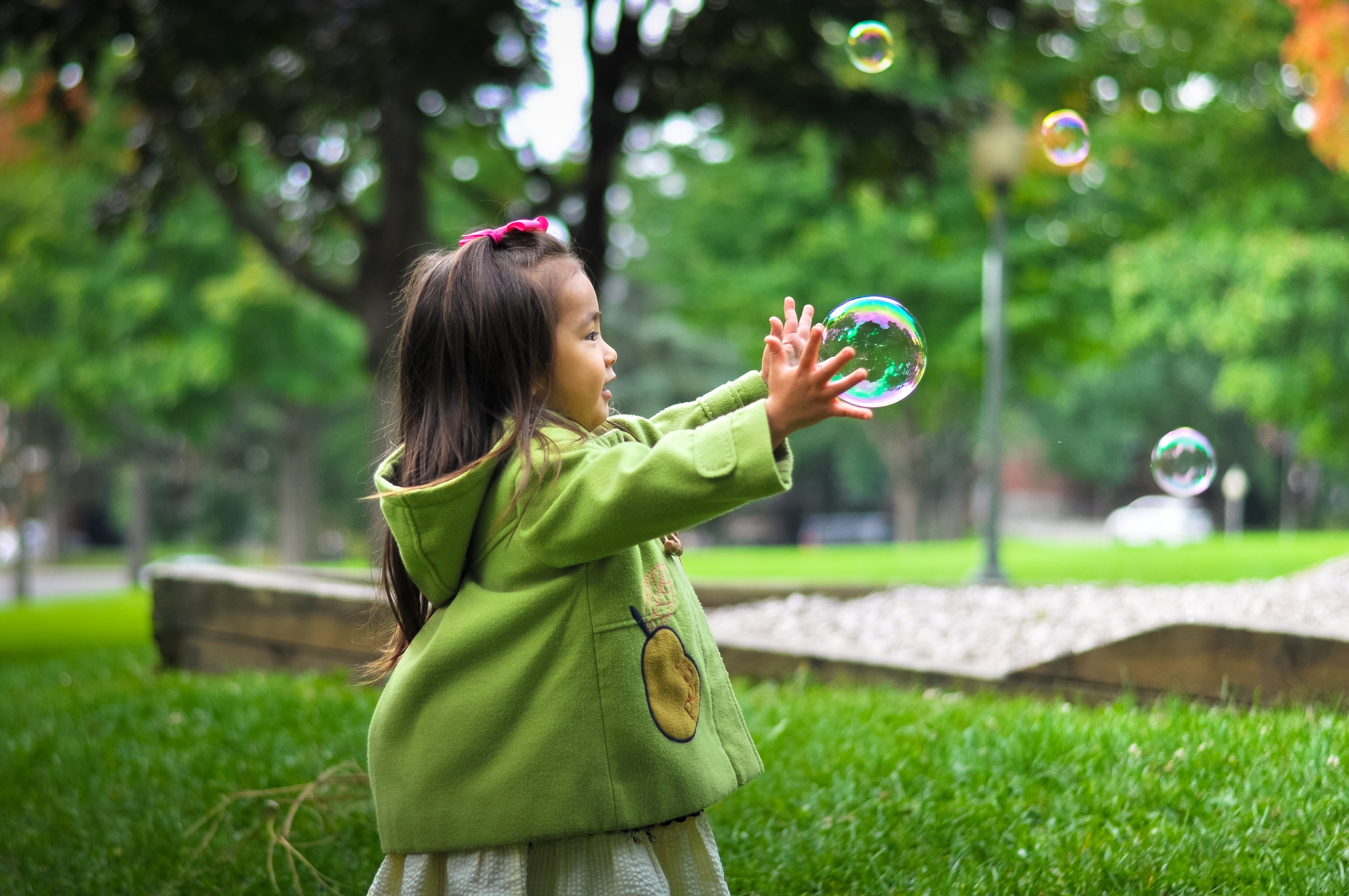 Little Girl Playing With Bubbles in a Park