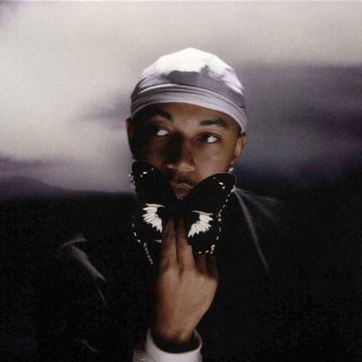 Album cover for Leave Another Day by John Carroll Kirby, featuring a warm, abstract design with soft gradients and a minimalist aesthetic. The artist holds a butterfly in front of his face.