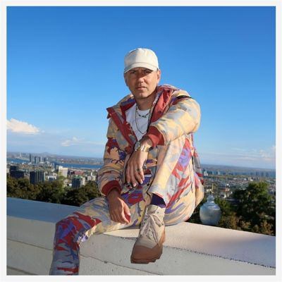 Album cover for In A Space Outta Dub by Nightmares on Wax vs. Adrian Sherwood, featuring abstract, space-inspired artwork with dark tones and layered, atmospheric visuals. Artist sits on a while wall.