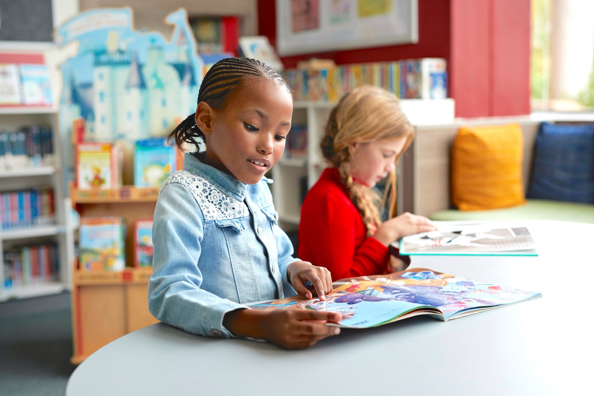 two young girls sitting at a table with books open two young girls sitting at a table with books open