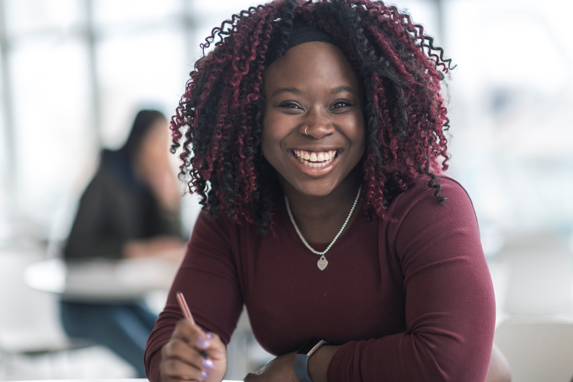 adult woman smiling at the camera holding a pen