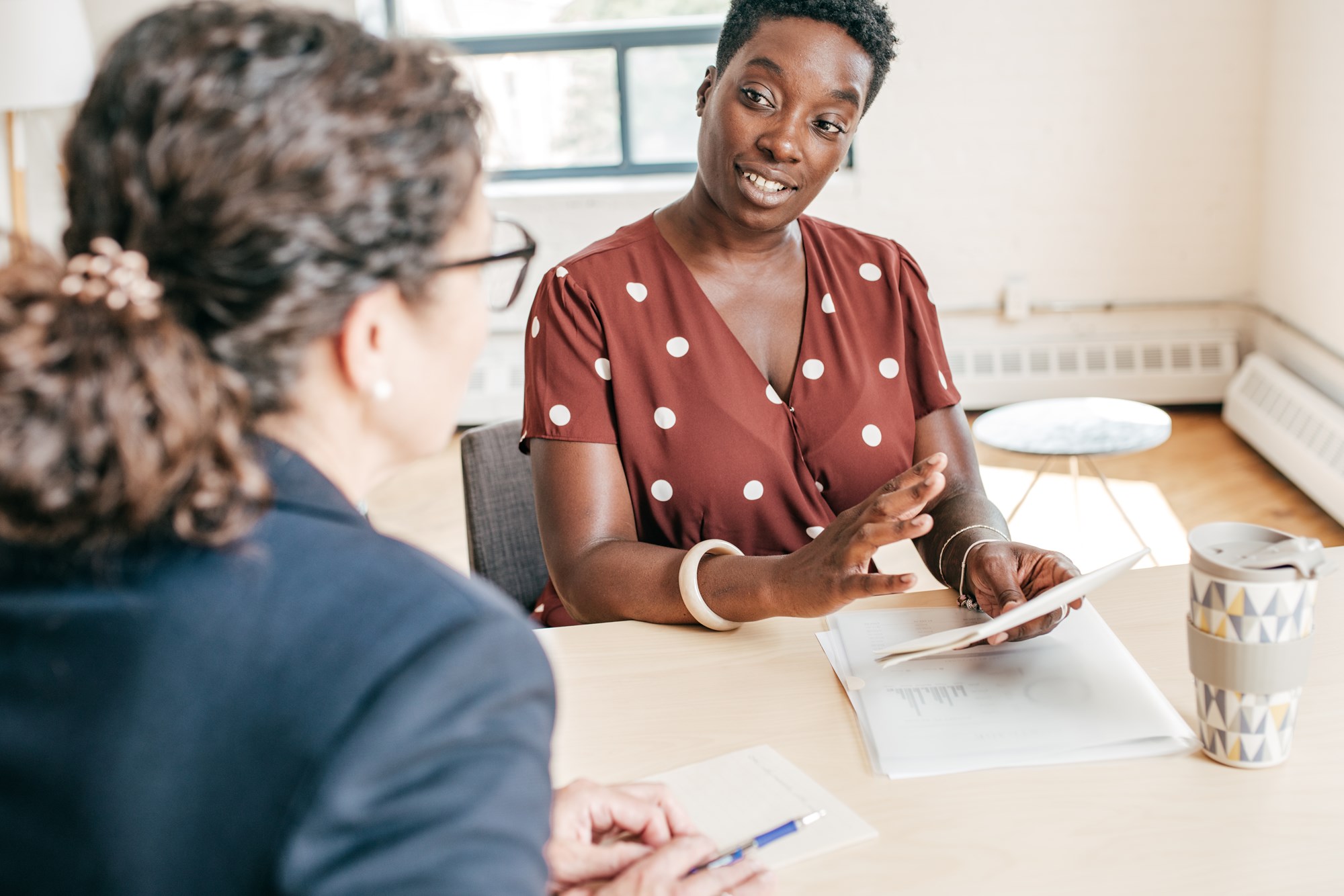 two women siting at a desk discussing two women siting at a desk discussing