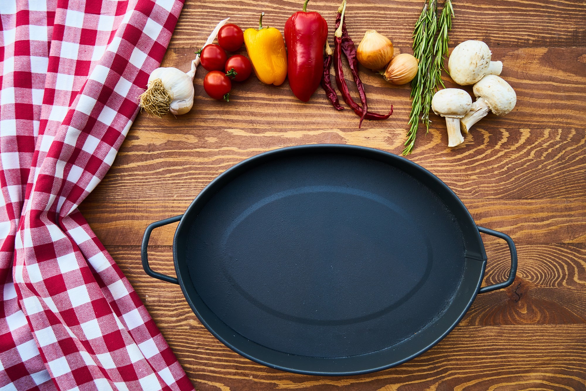 large cast iron skillet on a table with vegetables large cast iron skillet on a table with vegetables