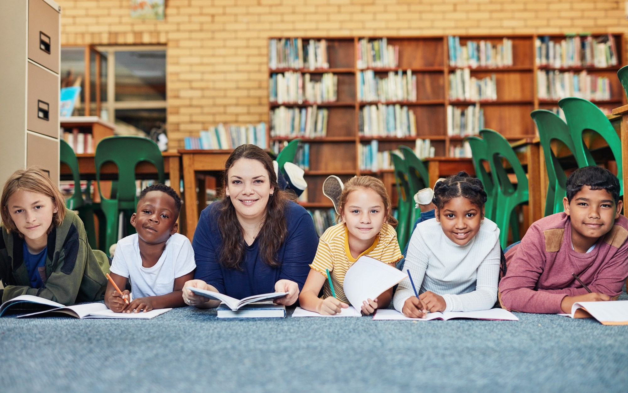 group of children and a librarian sitting on the library floor with books
