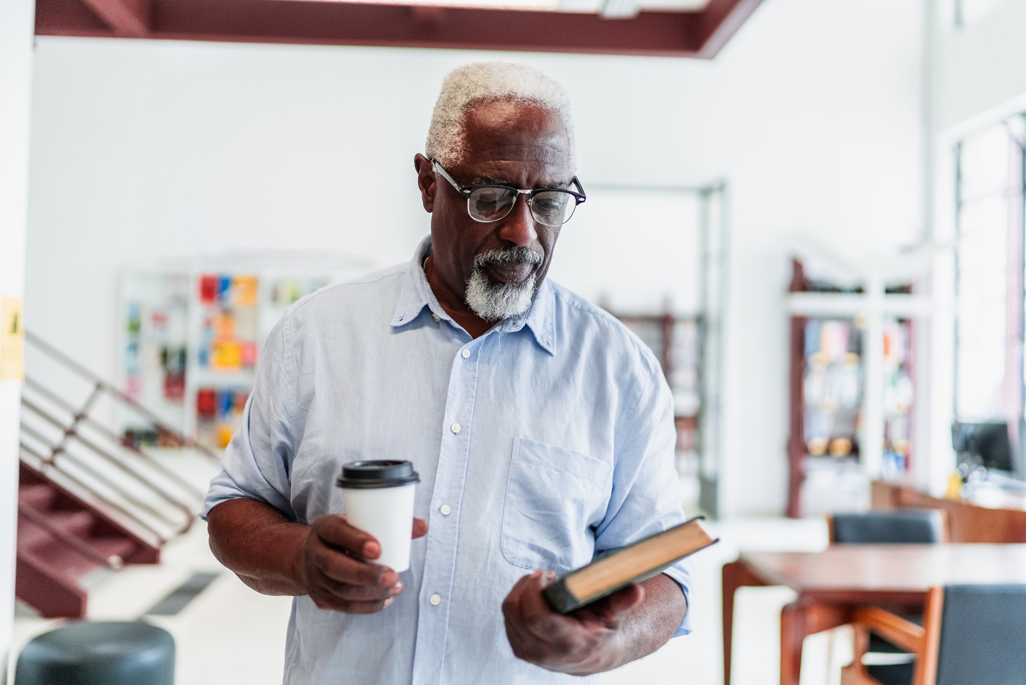 man holding a coffee cup and a book man holding a coffee cup and a book