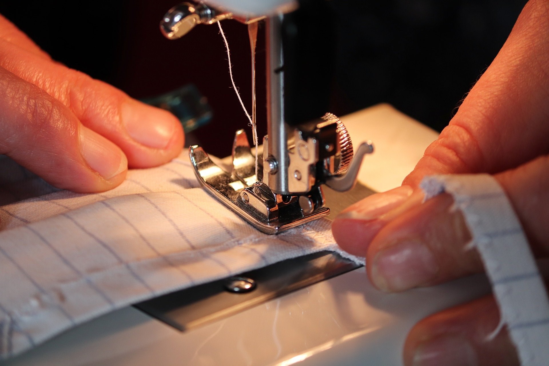 close up of hands using a sewing machine close up of hands using a sewing machine