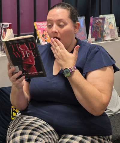Library worker holding the Trad Wife by Saratoga Schaefer.