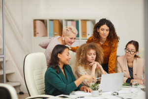 Five business women around a laptop.