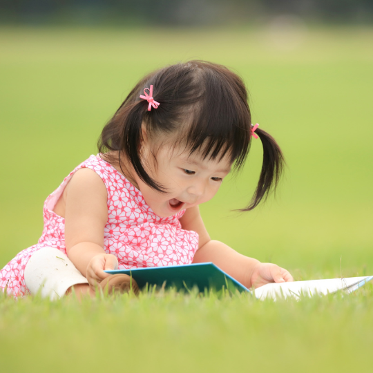 Happy child reading in the grass