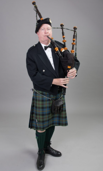 A man in full Scottish regalia playing bagpipes.