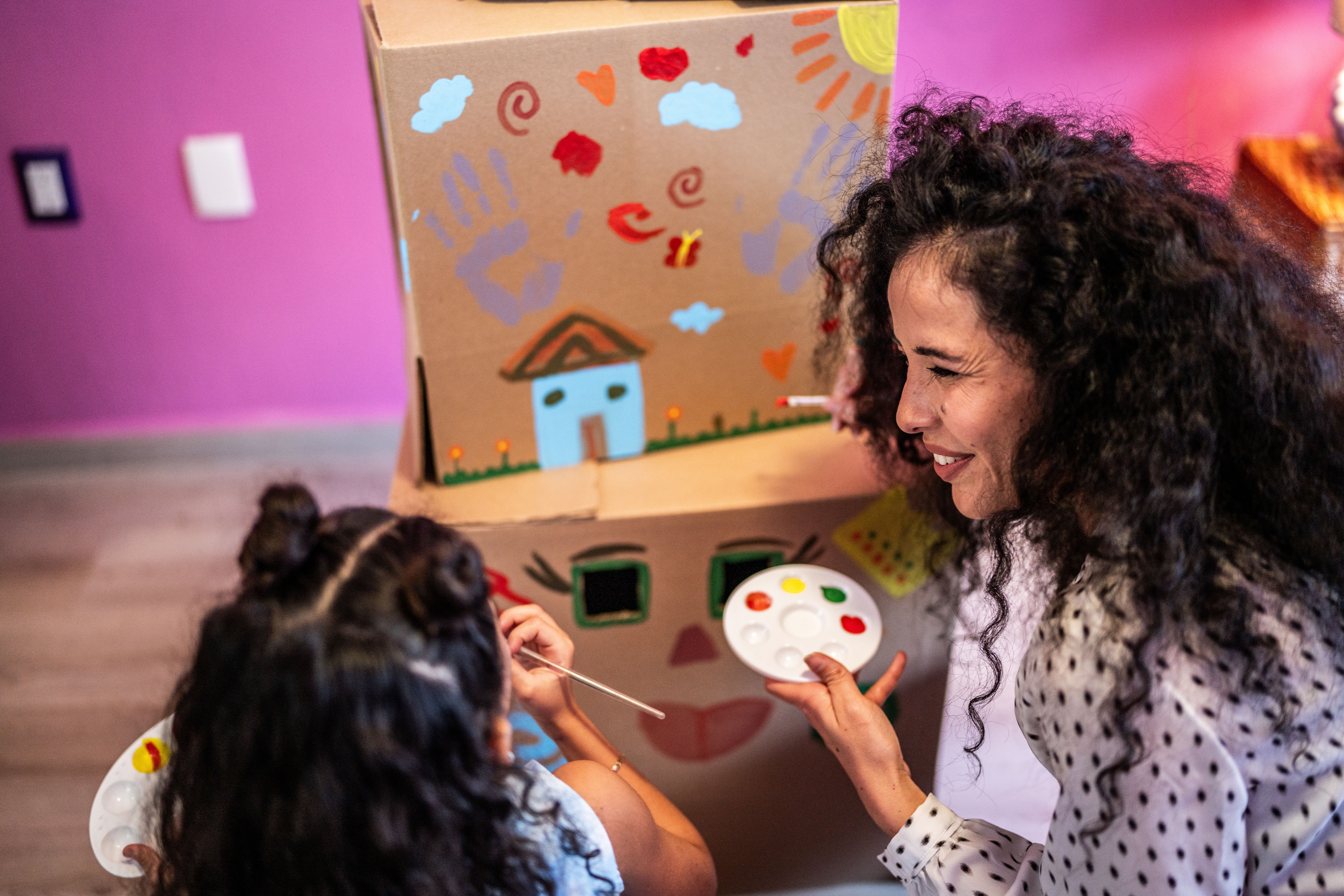 Happy Mother and Daughter Painting a Cardboard Box in the Bedroom at Home